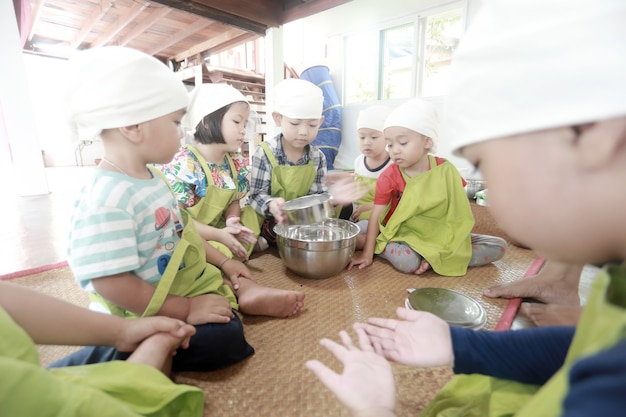 Groep aziatische kinderen die eten bereiden en thuis plezier hebben.