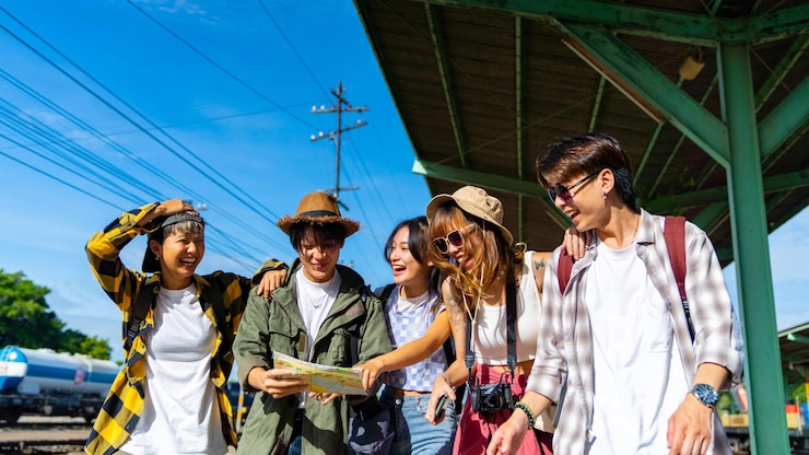 Foto groep aziatische mannen en vrouwen vrienden genieten van een leuke outdoor levensstijl en wachten op de trein op het treinstation tijdens een reis naar thailand tijdens de zomervakantie. jeugdcultuur en low-cost reisconcept
