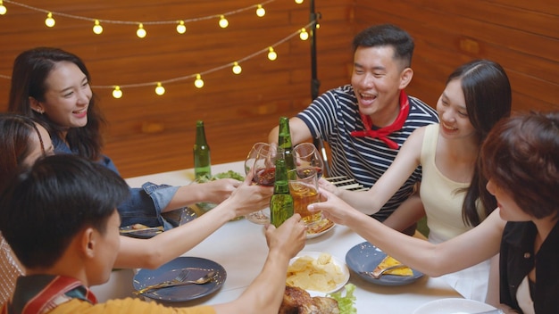 Groep Aziatische mensen feesten alcohol drinken proost bierfles en eten aan tafel zitten