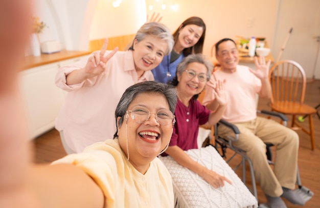 Foto groep aziatische senioren en verzorger die plezier hebben met selfie in het verpleeghuis