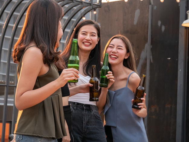 Groep aziatische vriend die en bij terraspartij toejuichen drinken. jongeren genieten en opknoping op het dak bij zonsondergang