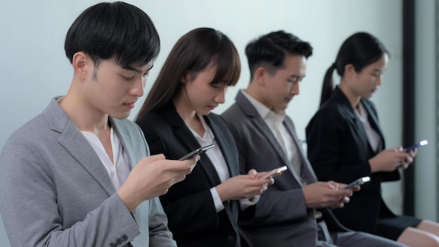 Foto groep aziatische zakenman en zakenvrouw kijken naar slimme mobiele telefoons op kantoor