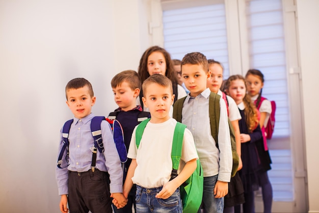 Groep basisschoolkinderen met rugzakken in schoolgang Terug naar schoolconcept