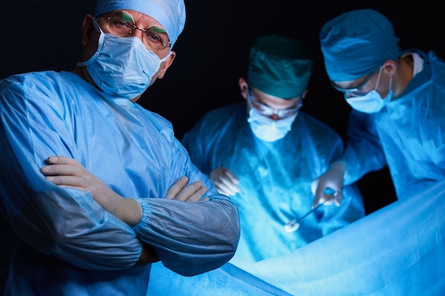 Groep chirurgen aan het werk in de operatiekamer, afgezwakt in blauw. Medisch team dat operatie uitvoert