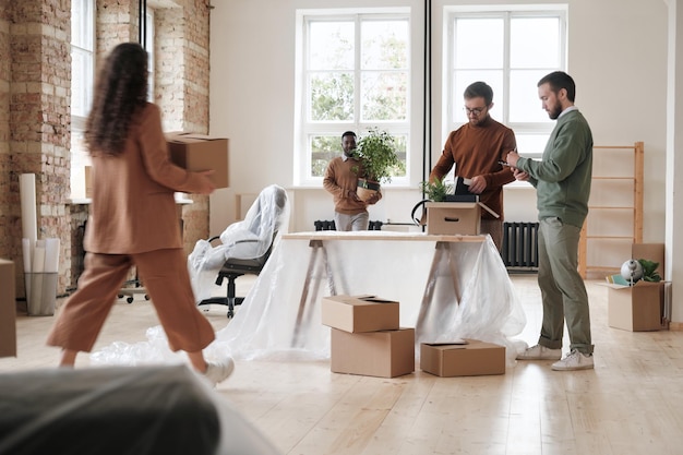 Groep collega's die dingen uitpakken in het nieuwe kantoor