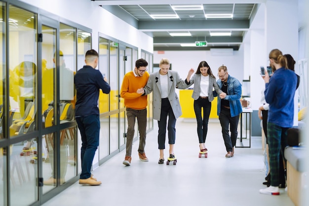 Groep collega's die plezier hebben met skateboard op kantoor