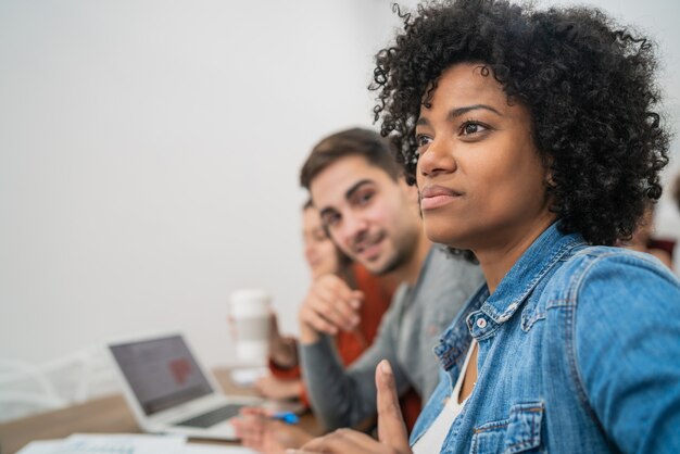 Groep creatieve bedrijfsmensen die aan collega luisteren die bureauvergadering aanpakken. Bedrijfs- en brainstormconcept.