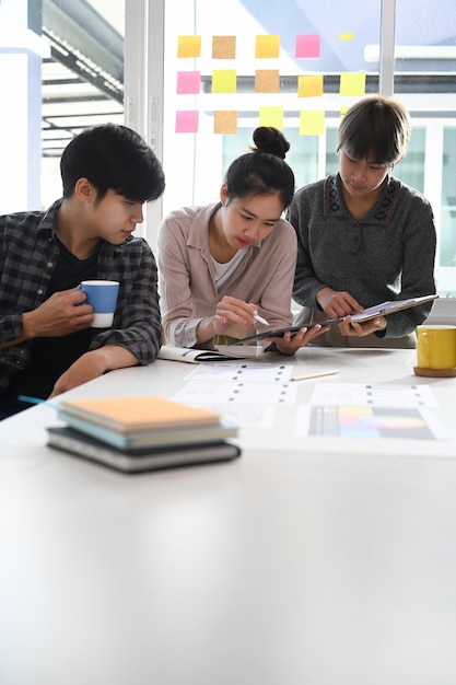 Groep creatieve ontwerper aan de vergadertafel voor het bespreken van de belangrijke kwesties van het nieuwe succesvolle startup-project.