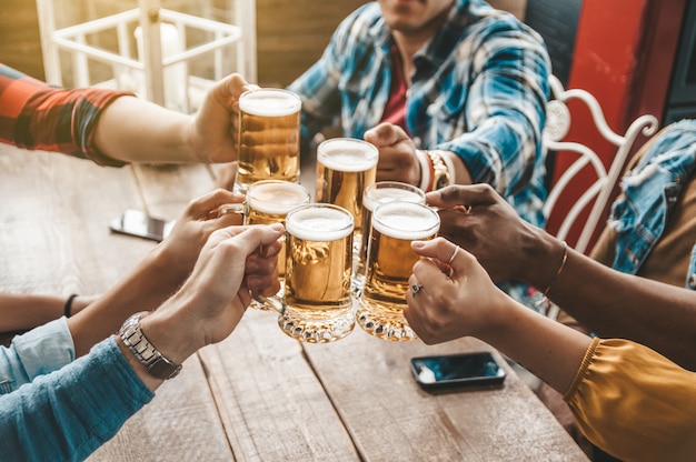 Groep die mensen en van een bier in brouwerijbar genieten roosteren - Vriendschapsconcept met jongeren die pret hebben samen