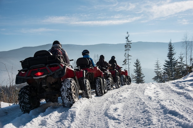 Groep die mensen vierlingfietsen op sneeuw boven de berg in de winter drijven