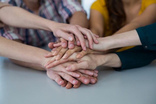 Groep directeuren die handstapel in bureau vormen