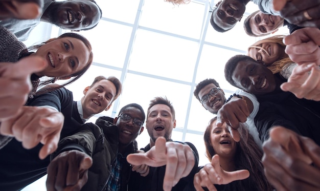 Groep diverse jonge mensen die in een cirkel staan en naar jou wijzen