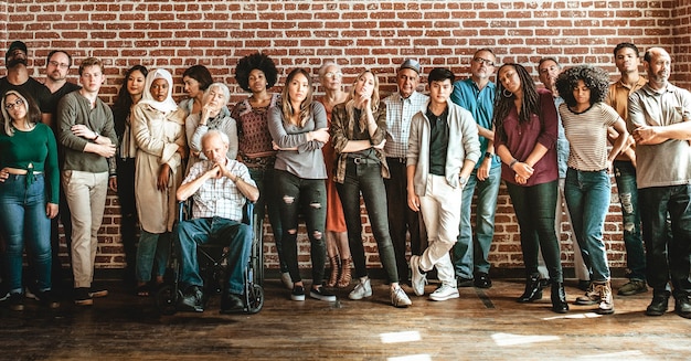 Groep diverse mensen die voor een bakstenen muur staan