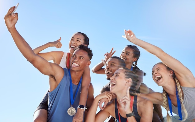 Groep diverse olympische atleten die een selfie nemen terwijl ze plezier hebben en handgebaren tonen Gelukkige en vrolijke lopers die samen een foto nemen Jonge mannelijke sprinter die een foto neemt met atleten