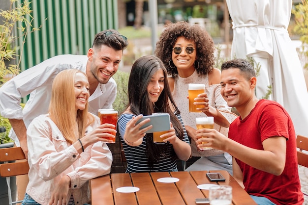 Groep diverse vrienden die selfie maken terwijl ze een biertje drinken