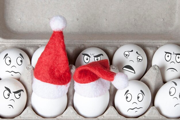 Groep eieren in speelgoed kerstmutsen met getekende emoties