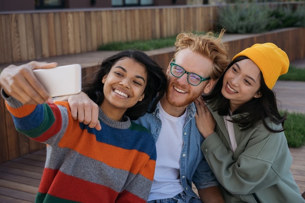 Groep emotionele multiraciale mensen die mobiele telefoon gebruiken die selfies nemen