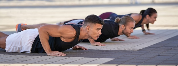 Groep fitnessmensen die push-ups doen in de stad