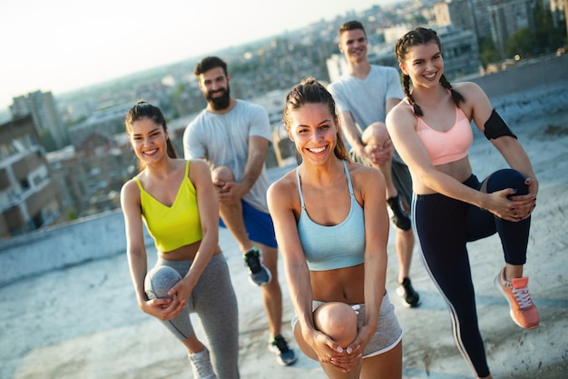 Foto groep fitte gelukkige mensen die buiten op het dak trainen