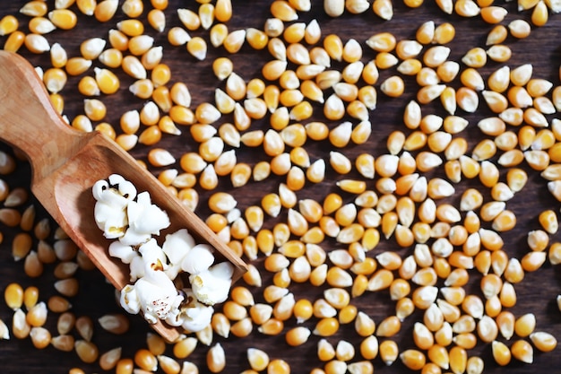 Groep gele rauwe maïskorrels suikermaïs. Graanzaden ingrediënt gouden maïskorrel. Houten tafel rijpe popcorn achtergrond.