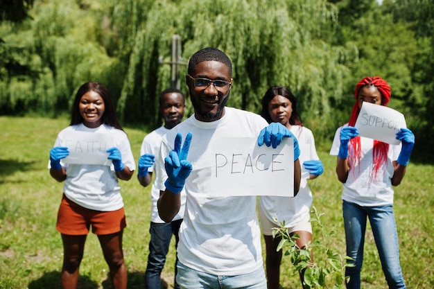 Groep gelukkige afrikaanse vrijwilligers houdt een leeg bord met vredesteken in park Afrika vrijwilligerswerk voor liefdadigheidsmensen en ecologieconcept