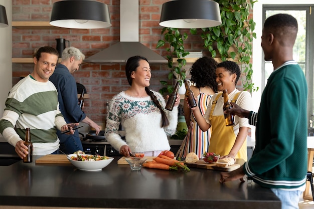 Groep gelukkige diverse vrouwelijke en mannelijke vrienden die bier drinken en samen koken in de keuken