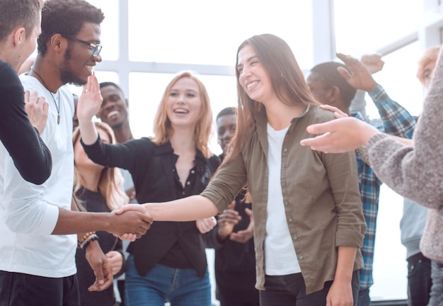 Groep gelukkige jonge mensen die hun collega feliciteren