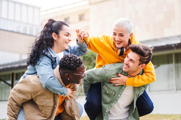 Groep gelukkige jonge middelbare scholieren die meeliften in campusvrienden die samen plezier hebben O