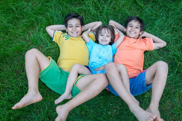 Groep gelukkige kinderen in de zomer die op groen gras liggen