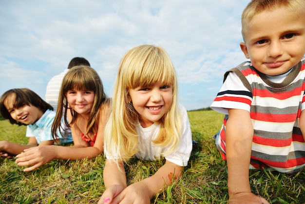 Groep gelukkige kinderen op de weide van het de zomergras in aard