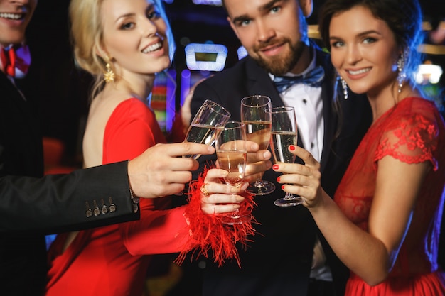 Groep gelukkige mensen die mousserende wijn in het casino drinken