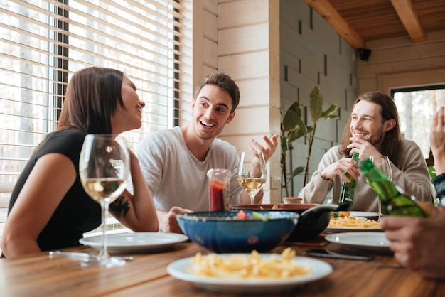 Groep gelukkige mensen eten en praten aan de tafel