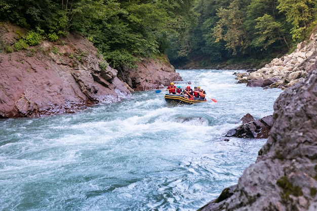 Groep gelukkige mensen met gids whitewater die en op rivier raften roeien.