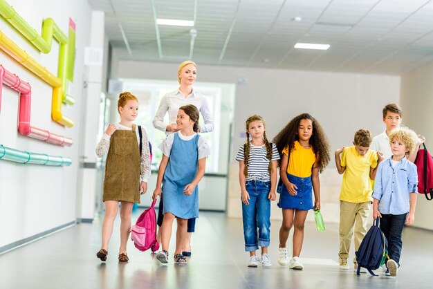 groep gelukkige multi-etnische klasgenoten die door de schoolcorridor lopen