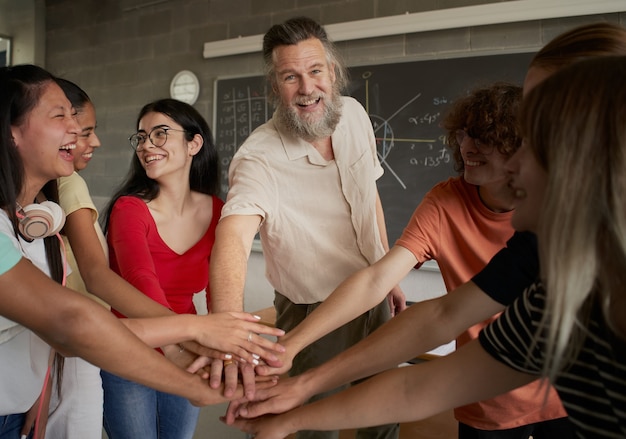 Groep gelukkige studenten die de hand steken met de leraar, de professor kijkt naar de camera