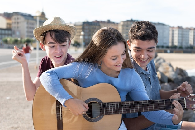 Groep gelukkige tieners die gitaar spelen en zingen in de stad