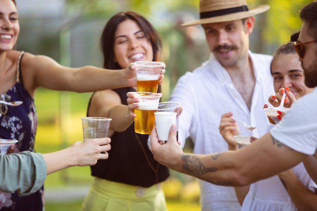 Foto groep gelukkige vrienden die bieren eten en drinken tijdens het barbecuediner op zonsondergangtijd