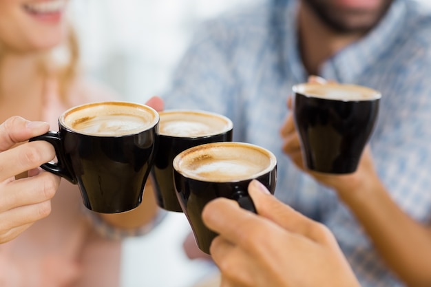 Foto groep gelukkige vrienden die kop van koffie roosteren