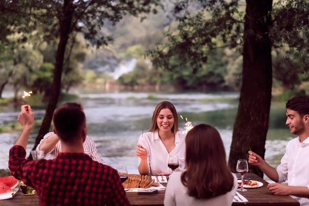 groep gelukkige vrienden hebben een picknick Frans etentje buiten tijdens de zomervakantie vakantie in de buurt van de rivier in de prachtige natuur