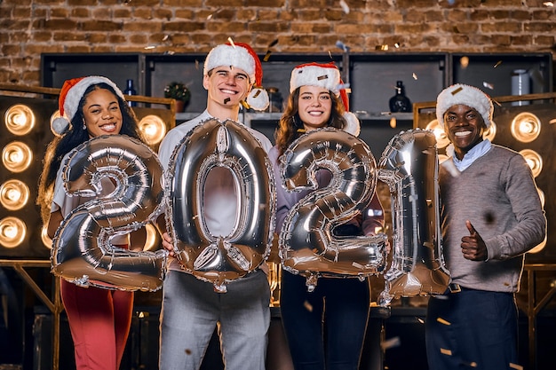 Groep gelukkige vrienden nieuwjaar vieren samen met ballonnen.