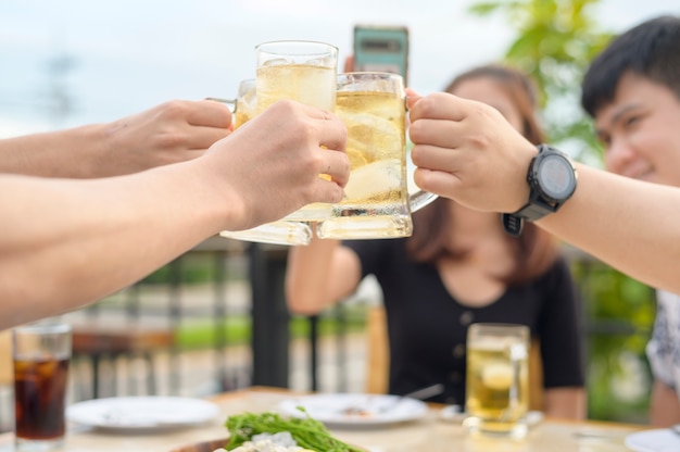 Groep gelukkige vrienden roosteren met een glas bier