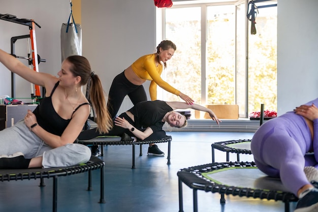 Groep gelukkige vrouwen die opwarmen voor de training in de sportschool die op trampoline springt