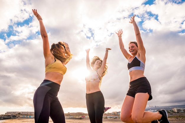 Foto groep gelukkige vrouwtjes springt op het strand na een fitnesssessie buiten