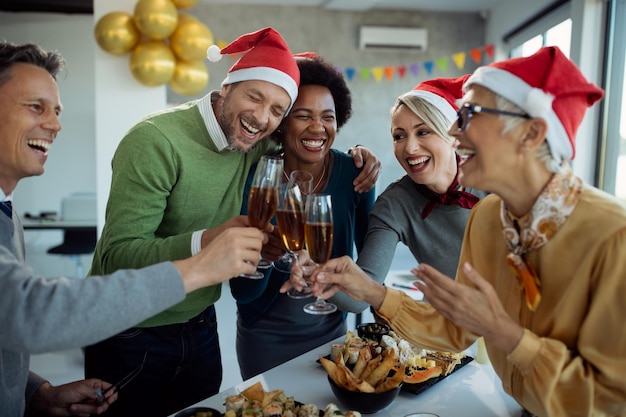 Foto groep gelukkige zakenmensen die roosteren met champagne op kerstfeest op kantoor