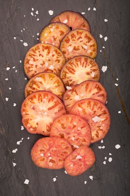 Groep gesneden raf tomaten met vlokzout op groene houten achtergrond