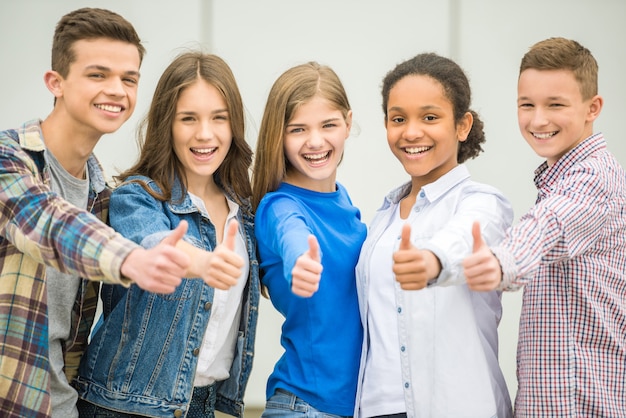 Groep glimlachende, vrolijke tieners die na de lessen plezier hebben