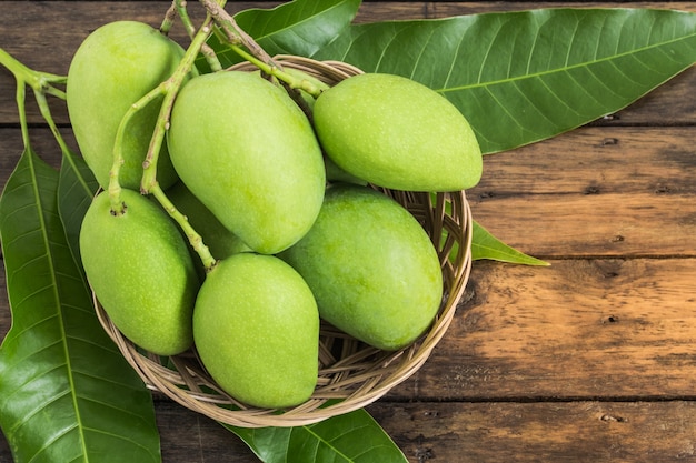 groep groene mango&#39;s in de mand op houten vloer