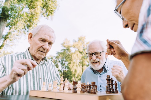 Groep hogere vrienden die schaakspel spelen bij het park. leefstijlconcepten over anciënniteit en derde leeftijd