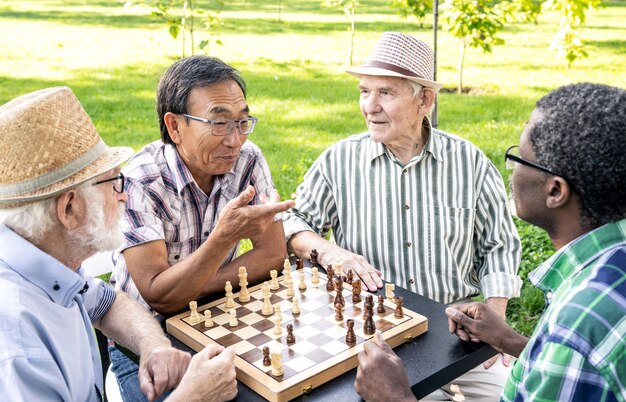 Groep hogere vrienden die schaakspel spelen bij het park. Leefstijlconcepten over anciënniteit en derde leeftijd