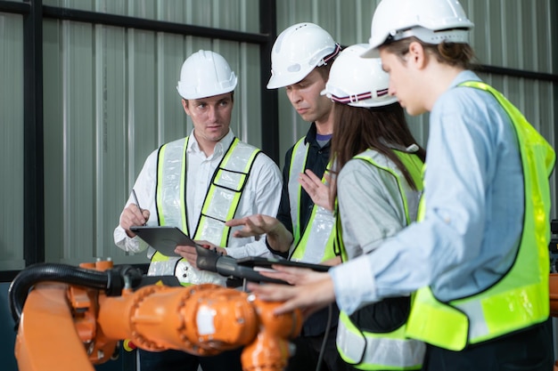 Groep ingenieurs en technici die samenwerken in een robotarmfabriek. Robotarm inspecteren